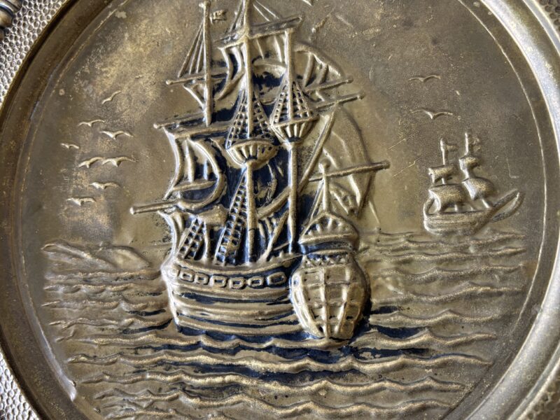Pair of vintage 14" English Hammered Brass plates at dinner table and sailing ship